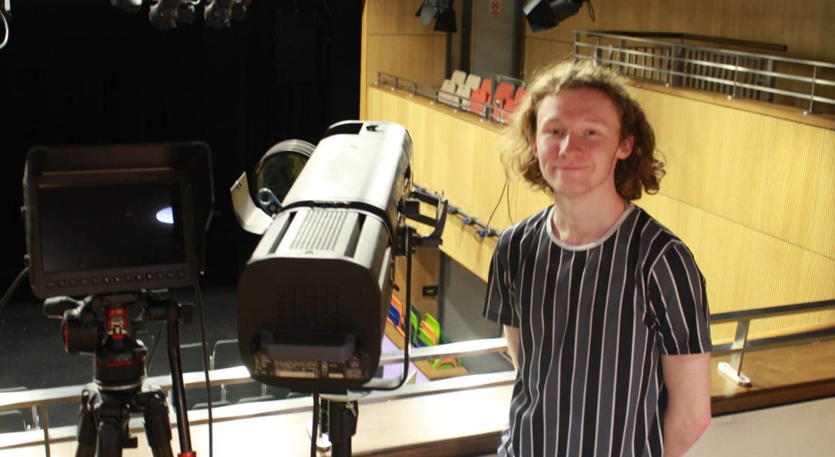 Picture of Rowan Magee standing beside lighting equipment in the college theatre.